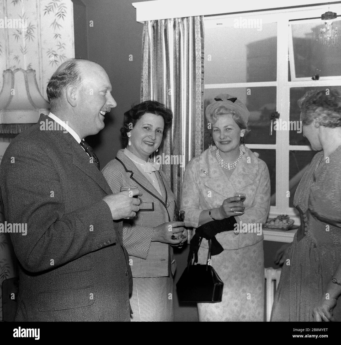 1962, historische, gut gekleidete, reife Menschen, die sich auf einer Jubiläumsfeier in einem Haus in England, Großbritannien, erfreuen. Stockfoto