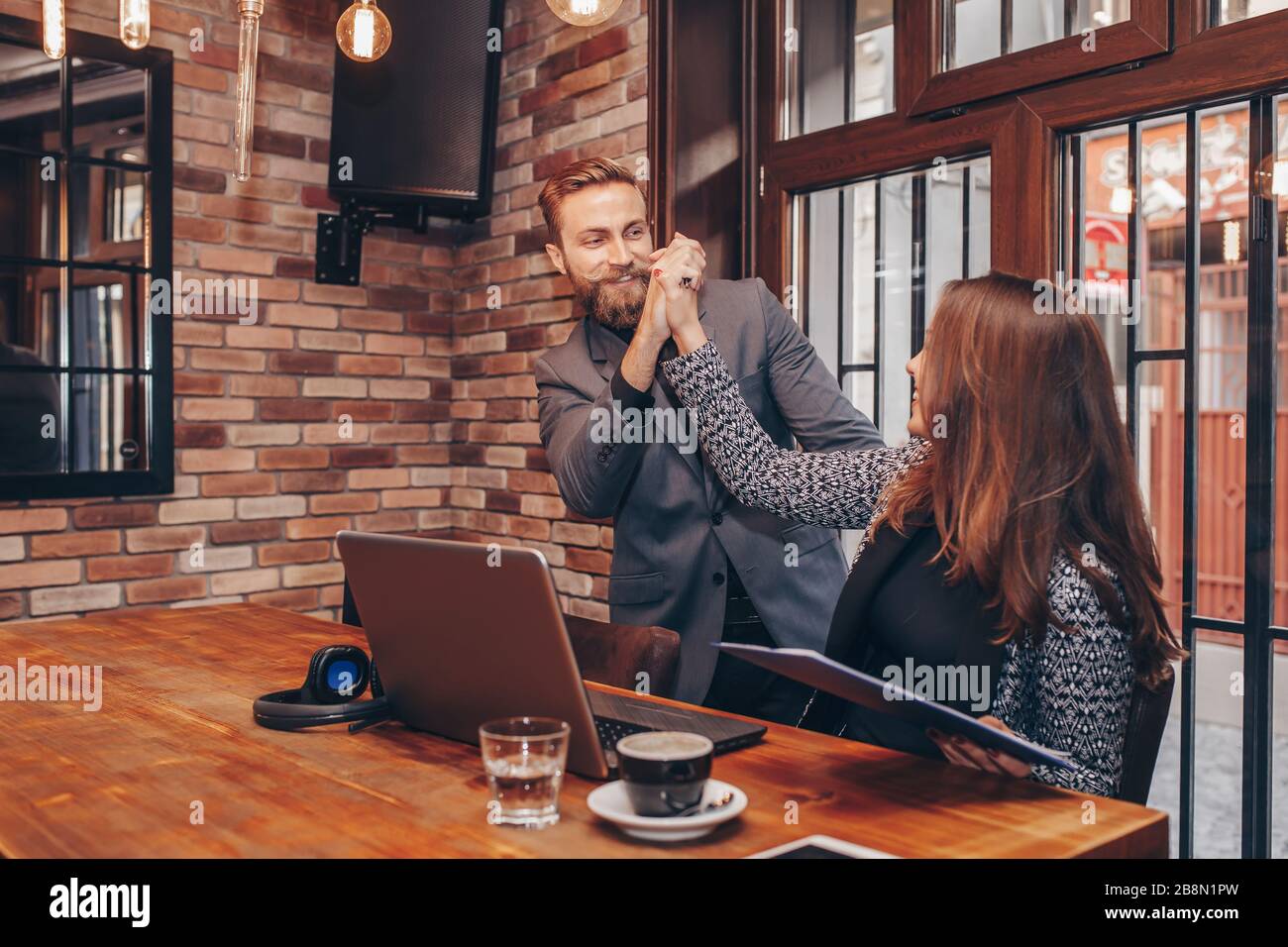 Fröhliche kaukasische Kollegen, die fünf hohe Personen geben und Erfolg feiern, gute Nachrichten online in einem Laptop oder Teamwork lesen. Motivierte Kollegen teilen Stockfoto