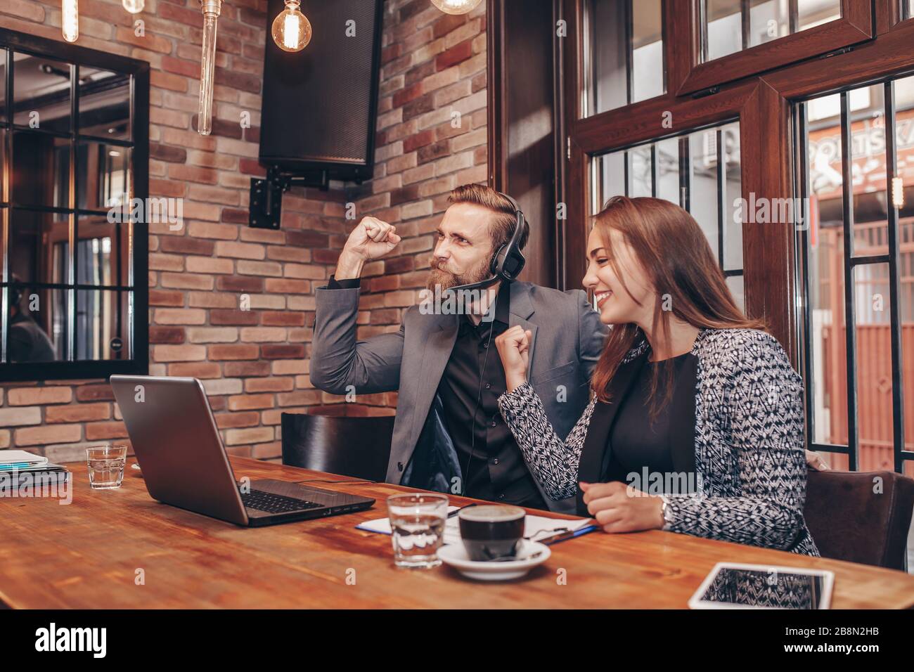 Glückliche, aufgeregte Geschäftsleute, die Erfolg feierten und mit Ja darüber lachen, während sie sich den Notebook-Monitor angusten und großartige Neuigkeiten erhalten. Erfolgreich Stockfoto