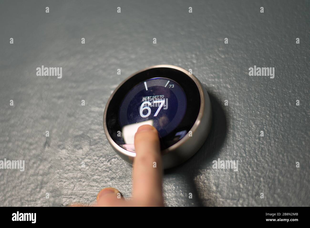 Handverstellung des Messuhr am Smart-Home-Thermostat. Drücken Sie die mittlere Taste, um Geld zu sparen, Heizung und Kühlung. Stockfoto