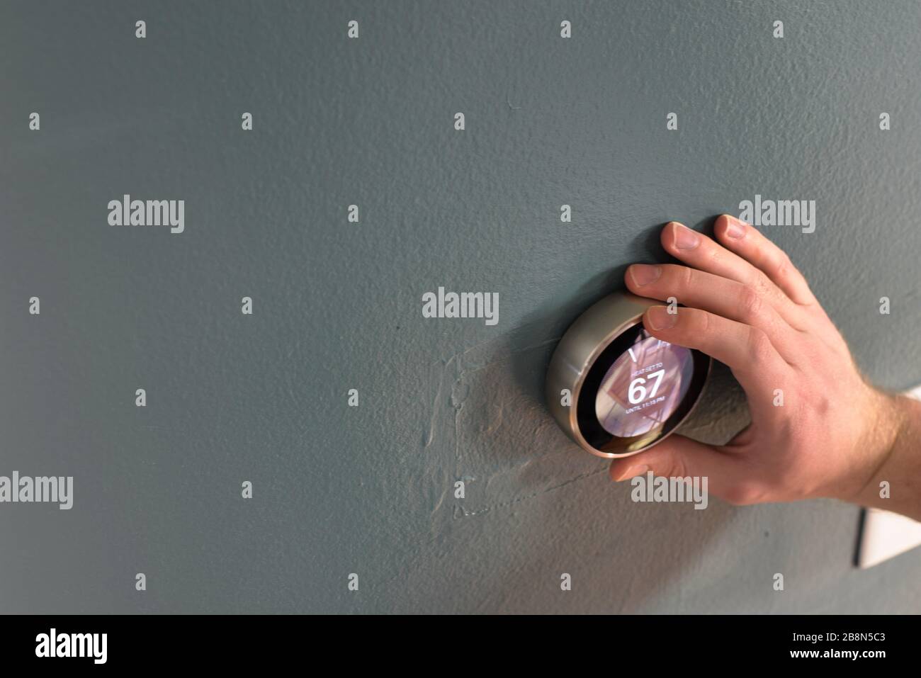 Handverstellung des Messuhr am Smart-Home-Thermostat. Drücken Sie die mittlere Taste, um Geld zu sparen, Heizung und Kühlung. Stockfoto