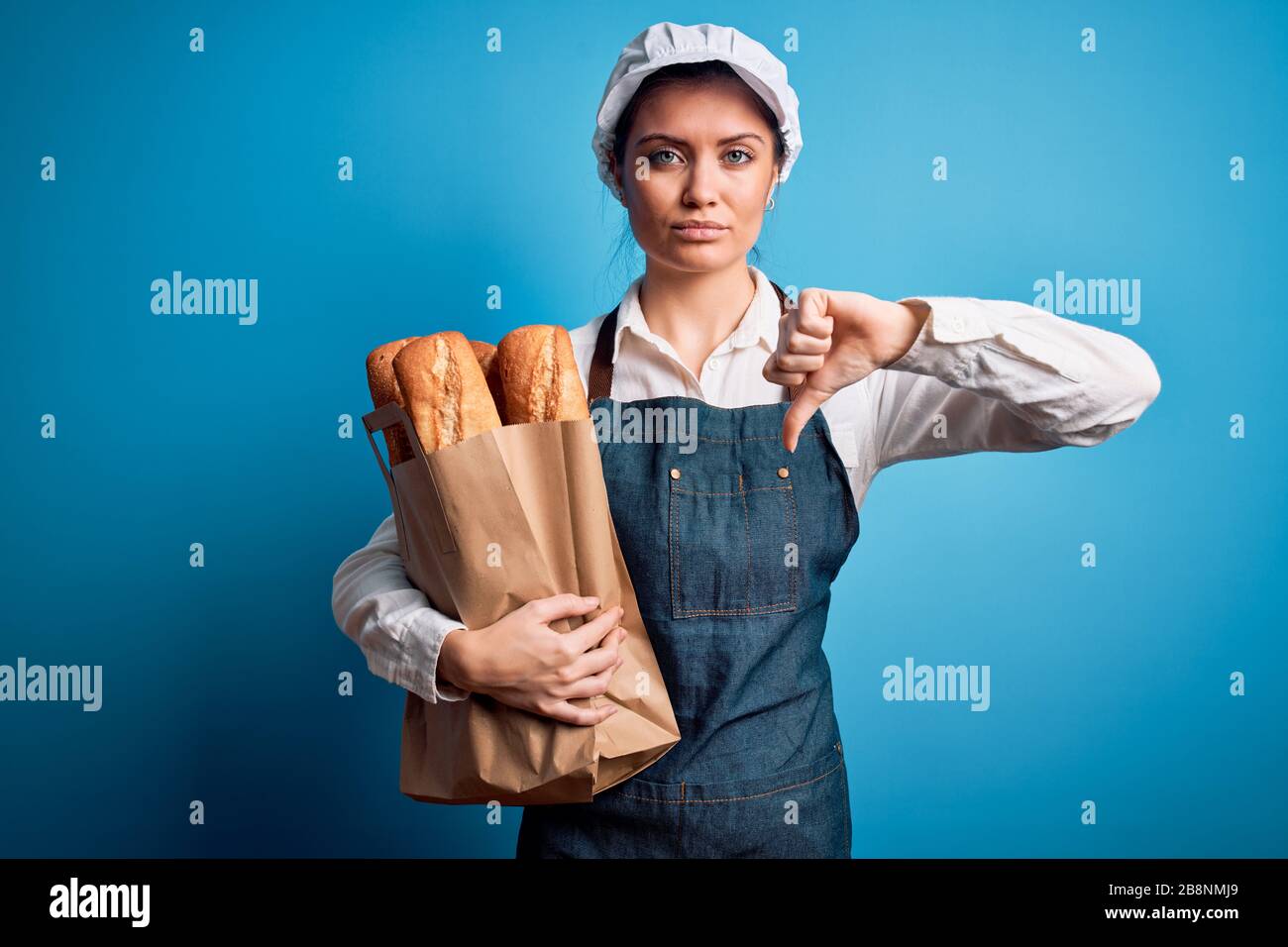 Junge schöne Bäckerin mit blauen Augen, die Papiertüte mit Brot mit ...