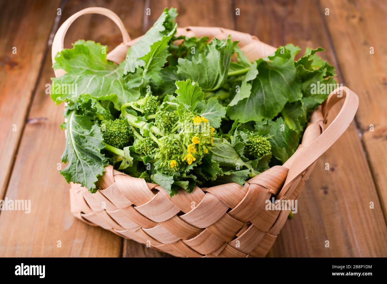 Rohbio Turnip Greens auf braunem Holzhintergrund . Korb mit frischem grünen Gemüse . Italienische Küche. Oben Stockfoto