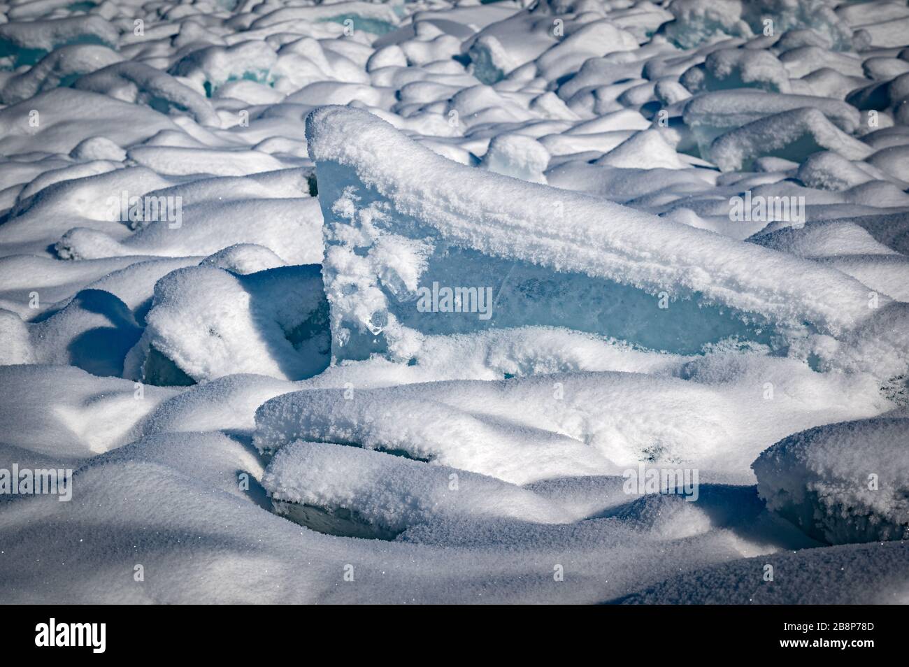 Durchsichtiges blaues Eis schwimmt an einem sonnigen Tag in Eishömmeln gegen einen blauen Himmel. Ungewöhnliche Winterlandschaft des zugefrorenen Baikalsee. Natürliche Kälte B. Stockfoto