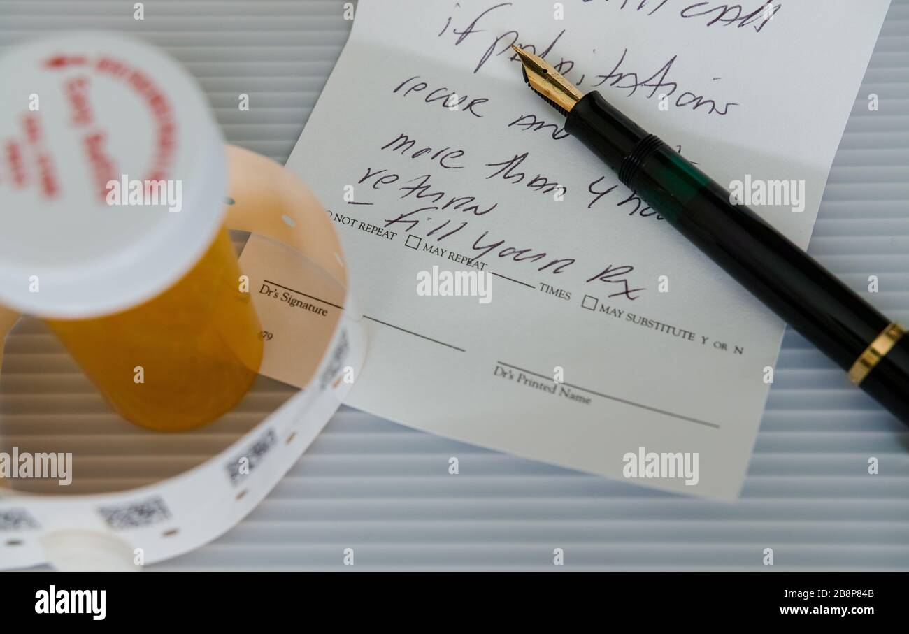 Ein Füllfederhalter auf einem Rezept für Herzprobleme. Daneben ein Medizinbehälter und ein Armband. Stockfoto