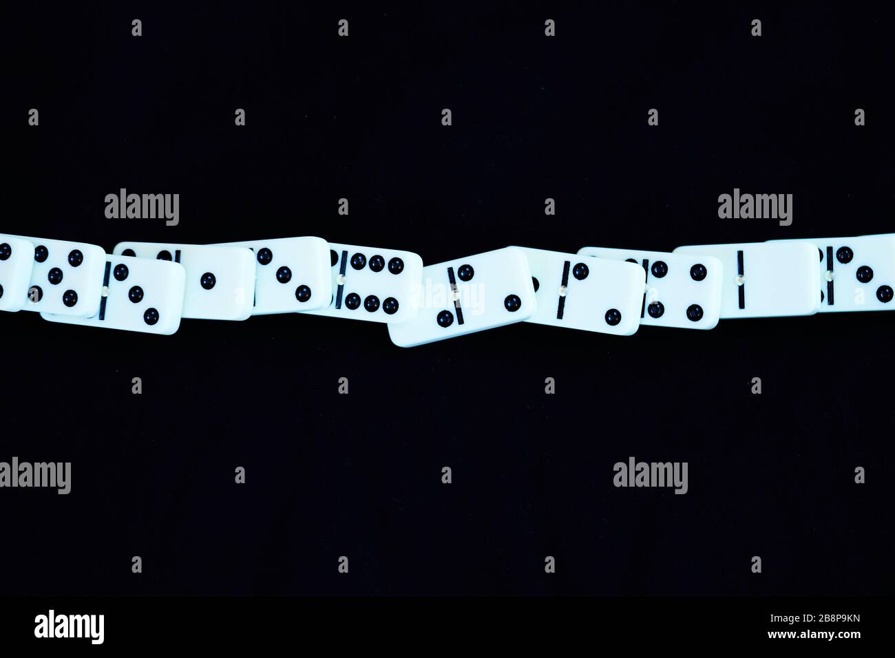 Weißer Dominostein, der ohne Unterbrechung von links nach rechts in gerader Linie fällt. Konzept für Coronavirus Kovid 19, ohne Eingriff des Dominoeffekts Con Stockfoto