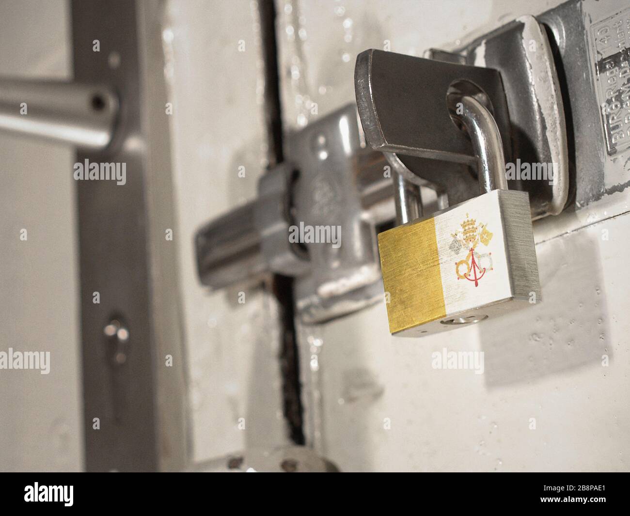 Eine verschraubte Tür, die mit einem Vorhängeschloss mit der Nationalflaggen der Vatikanstadt darauf gesichert ist.(Serie) Stockfoto