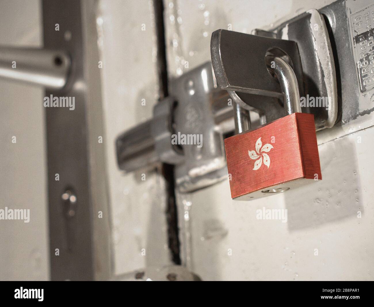 Eine verschraubte Tür, die mit einem Vorhängeschloss mit der Nationalflaggen von Hongkong darauf gesichert ist.(Serie) Stockfoto