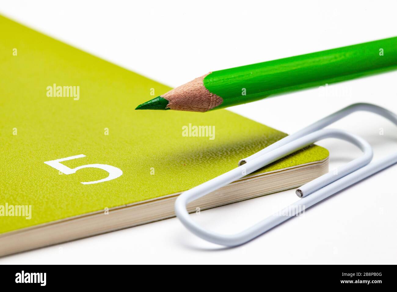 Veranstalter für den Monat Mai, grüner Bleistift und weiße Büroklammer auf dem weißen Tisch. Stockfoto