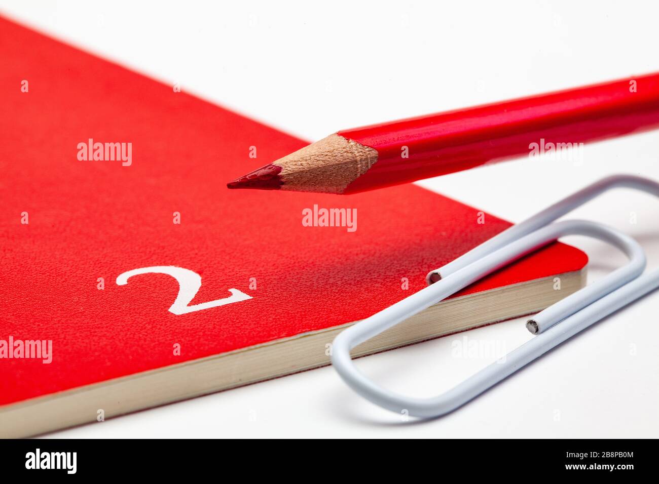 Veranstalter für den Monat Februar, roter Bleistift und weißer Büroklammer auf dem weißen Tisch. Stockfoto