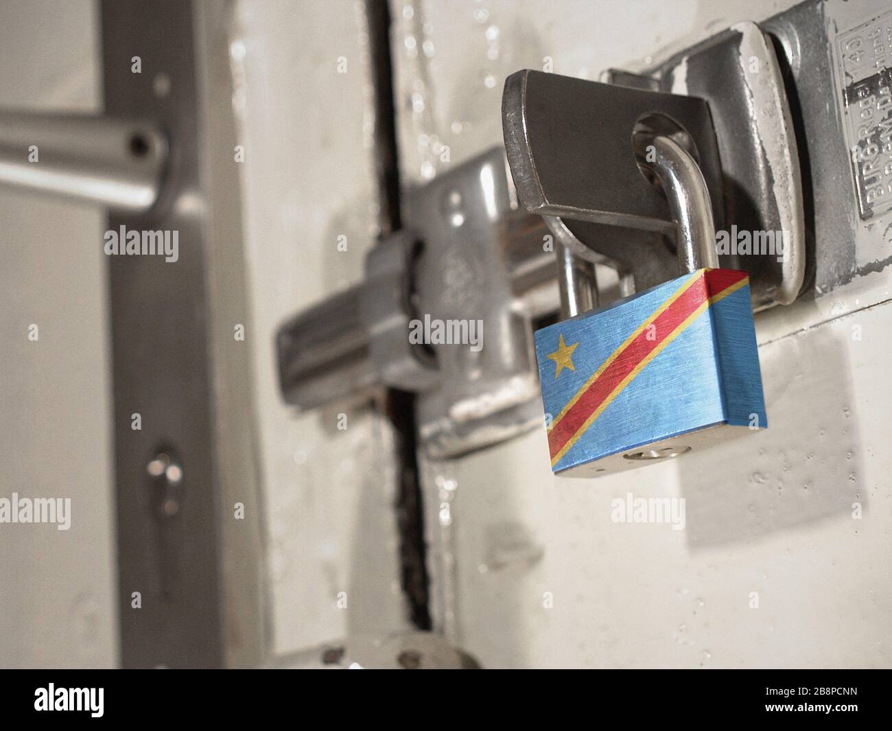 Eine verschraubte Tür, die mit einem Vorhängeschloss mit der Nationalflaggen der Demokratischen Republik Kongo darauf gesichert ist.(Serie) Stockfoto