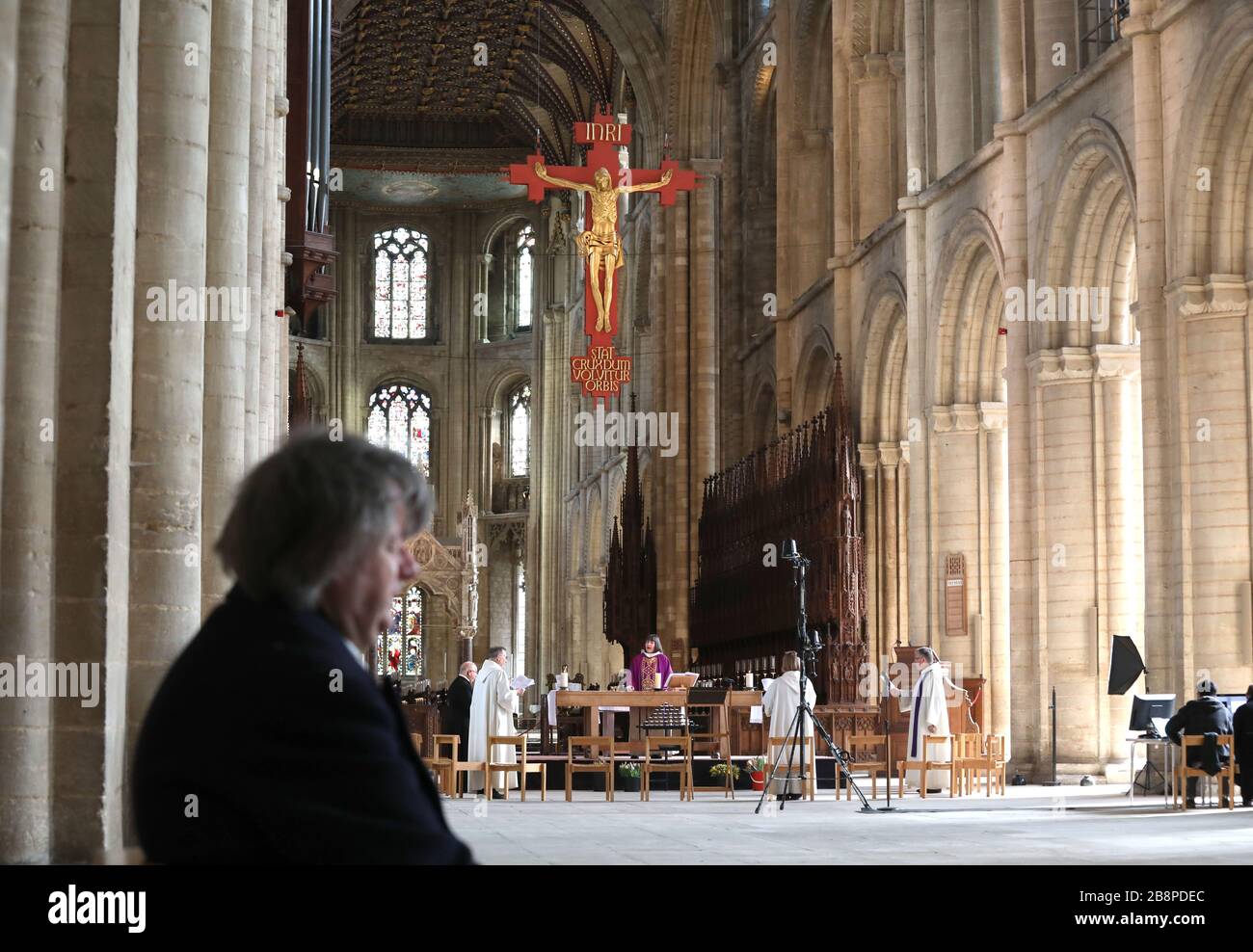 Peterborough, Cambridgeshire, Großbritannien. März 2020. Eine alleinstehende Anbeterin hört als Canon Sarah Brown, steht unter sozial distanzierten Stühlen für ihre Geistliche, wie sie während des Mothering Sunday Service in der Peterborough Cathedral spricht, wird ohne eine Gemeinde abgehalten, da es live über das Internet gestreamt wird, damit Menschen überall zusehen können, wo sie können. Die Pandemiekrise des COVID-19 Coronavirus geht weiter, wo Cafés, Bars, Restaurants, Turnhallen und Freizeitzentren geschlossen werden müssen, sowie Kultstätten wie Kirchen, Kathedalen, Moscheen und Synagogenbauten. Credit: Paul Marriott/Alamy Live News Stockfoto