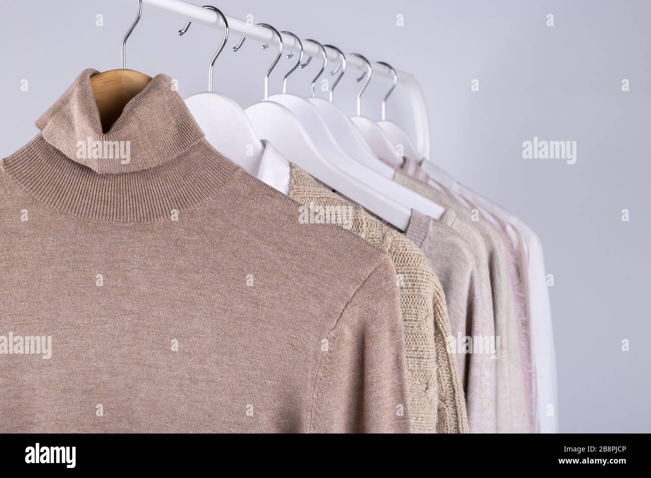 Weibliche Federkleidung, die an einem Regal hängt und in Pastellfarben aufgeht Stockfoto