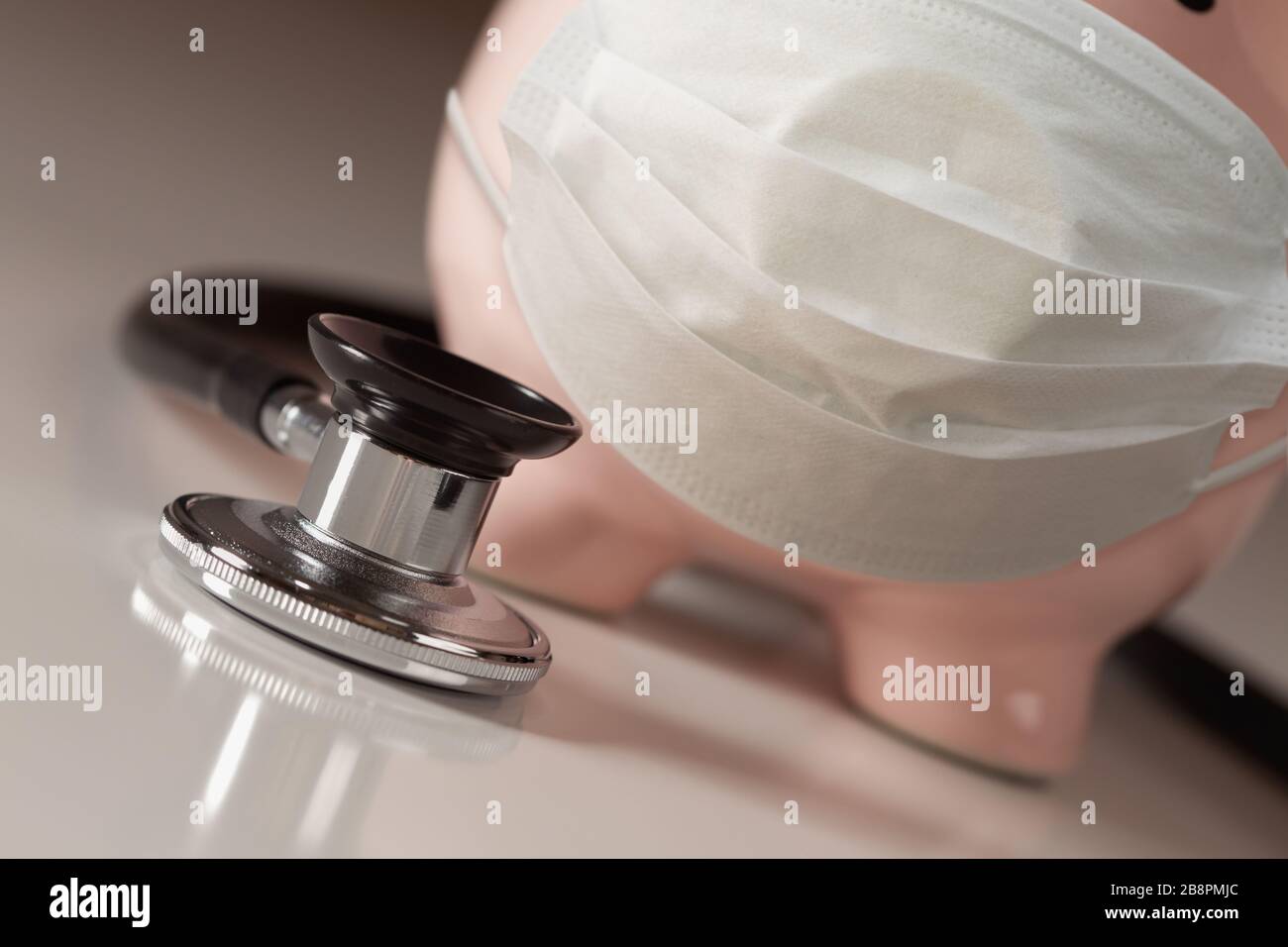 Stethoskop und Piggy Bank tragen medizinische Gesichtsmaske. Stockfoto