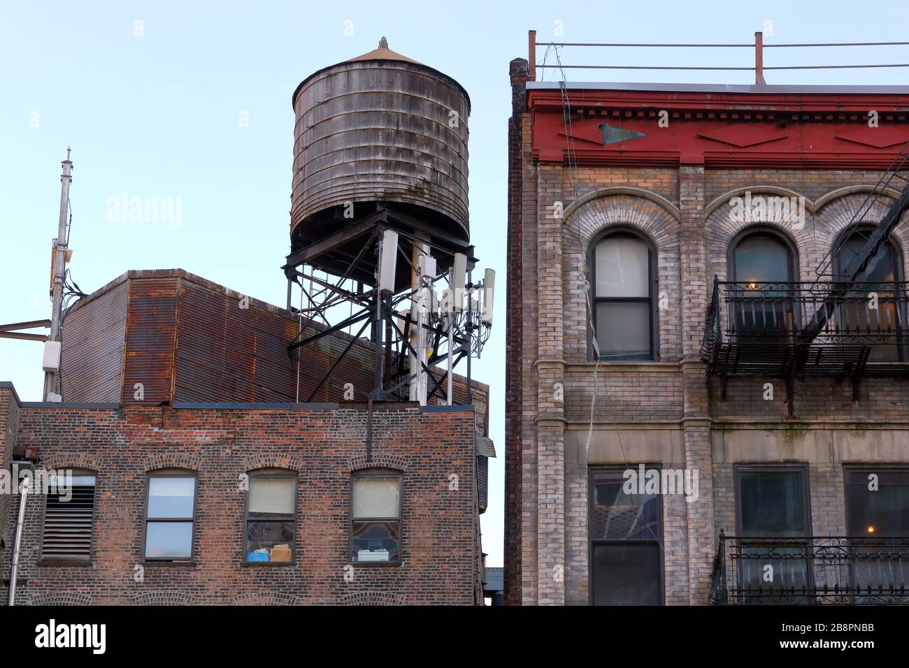 Ein Wassertank aus Holz auf dem Dach eines Industrieloftgebäudes neben  einem Mietsgebäude in New York City Stockfotografie - Alamy