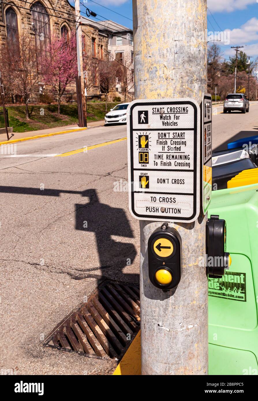 Eine Telefonstange aus Metall mit einem Crosswalk-Schild und Knöpfen mit dahinter liegenden Zeitungskästen in der Nachbarschaft von Squirrel Hill, Pittsburgh, Pennsylvania Stockfoto