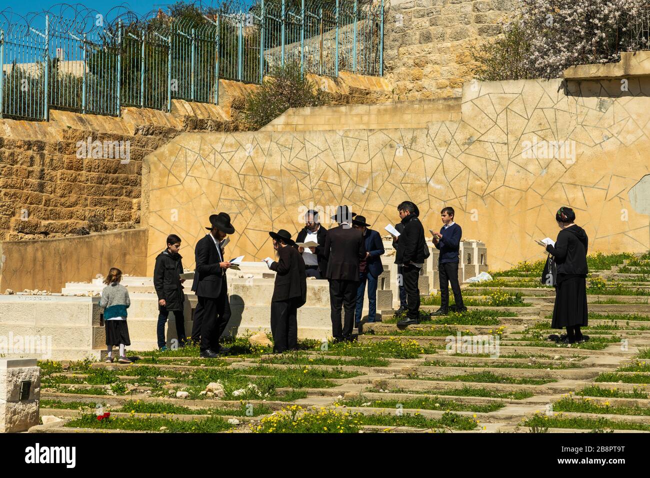 Eine Gruppe von orthodoxen Juden, die auf einem Friedhof auf dem Ölberg, Jerusalem, Israel und dem Nahen Osten beten. Stockfoto