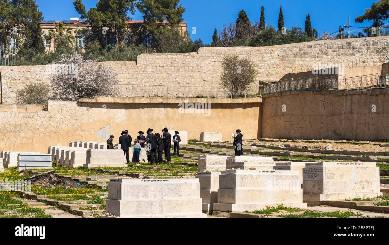 Eine Gruppe von orthodoxen Juden, die auf einem Friedhof auf dem Ölberg, Jerusalem, Israel und dem Nahen Osten beten. Stockfoto