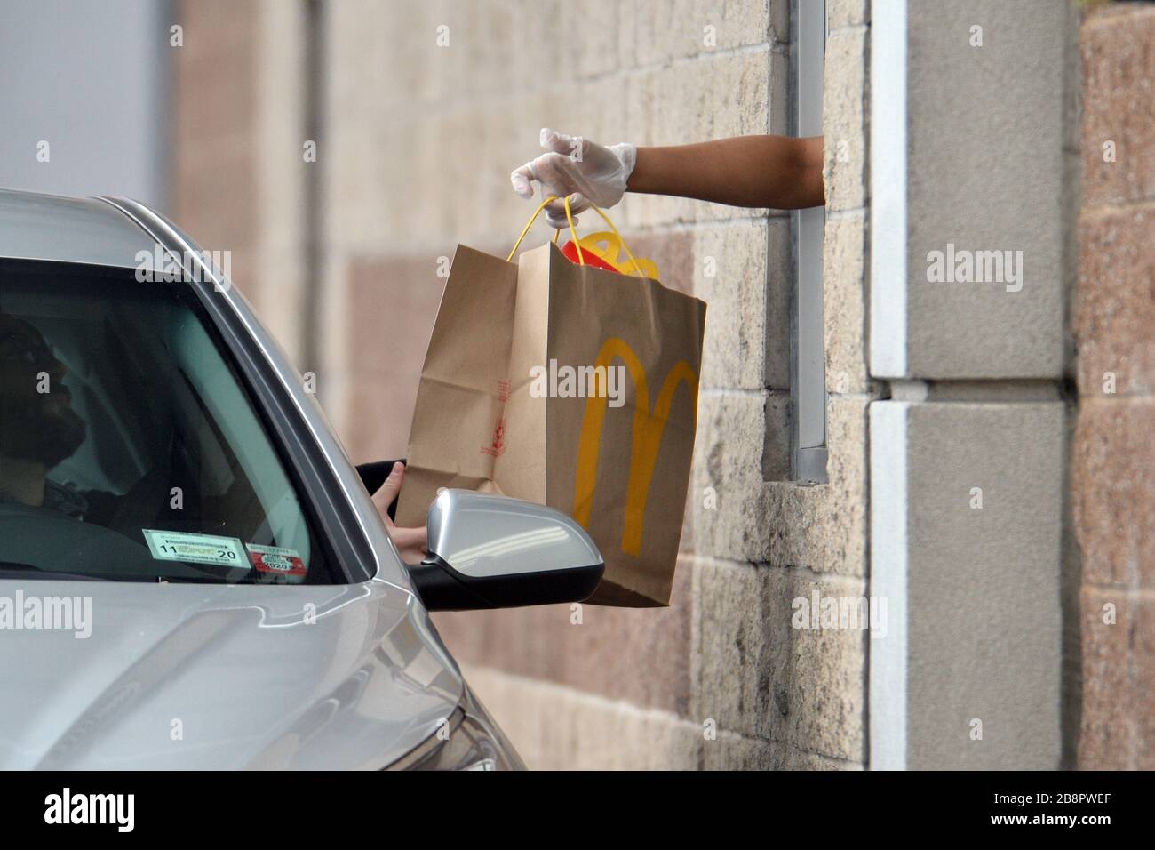 New York City, USA. März 2020. Da alle Restaurants nur Lebensmittel für die Mitnehmerdienste vorbereiten dürfen, bestellt ein Durchfahrt-Kunde einen Schutzhandschuh, der Mitarbeiter von McDonald's trägt, im New York City Borough of Queens, NY, am 22. März 2020. Mit mehr als 9000 bestätigten Fällen von COVID-19 und 63 Todesfällen in New York City wird am Sonntag, den 22. März 2020, um 20:00 Uhr eine "Bleibe zu Hause"-Anordnung und die Schließung aller nicht essentiellen Unternehmen wirksam. (Anthony Behar/Sipa USA) Credit: SIPA USA/Alamy Live News Stockfoto