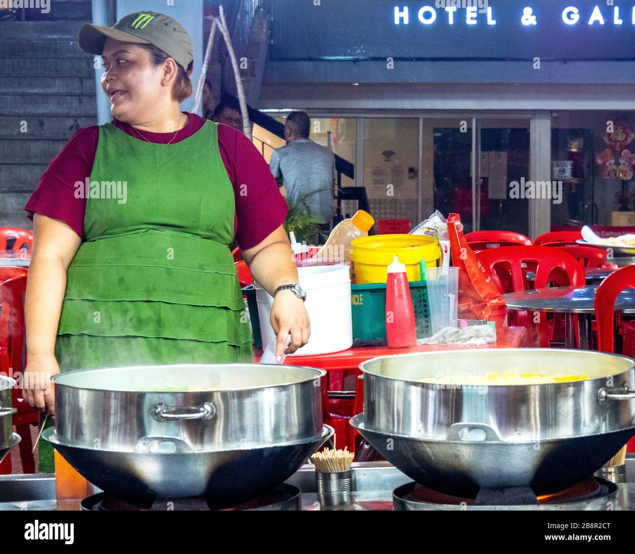 Köchin steht vor großen Pfannen und kocht Nudeln in einem Restaurant im Freien Jalan Alor Bukit Bintang Kuala Lumpur Malaysia. Stockfoto