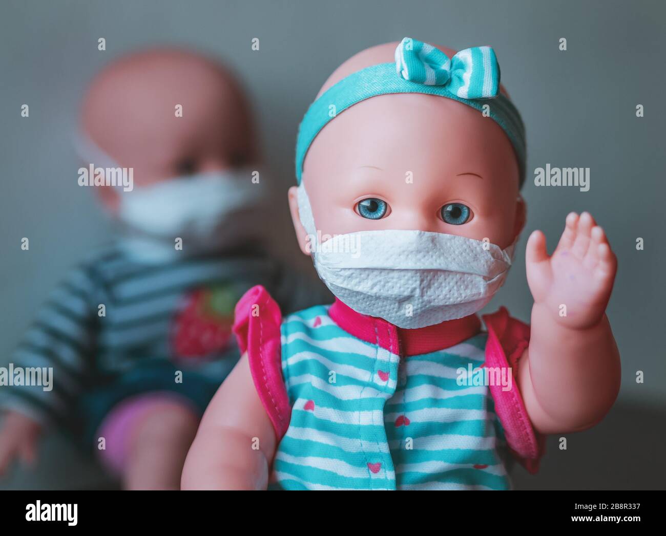 Eine ansteckende Babypuppe, bei der die verunreinigte Hand angehoben wird, dahinter befindet sich eine weitere Puppe mit einer Maske Stockfoto