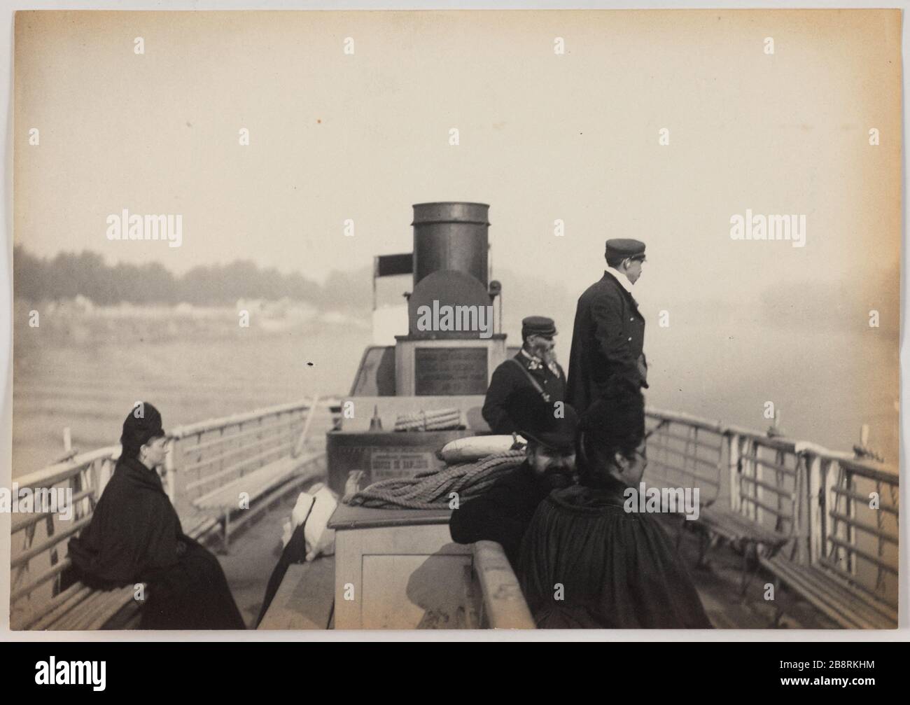 Sèvres / Steamboat Suresnes. Menschen auf dem Deck eines Dampfschiffs Suresnes Sèvres Blancard, Hippolyte. Sèvres / Bateau à Vapeur de Suresnes. "Personnes sur le pont d'un bateau à vapeur de Suresnes à Sèvres". Tirage au platine. vers 1890-1890. Paris, musée Carnavalet. Stockfoto