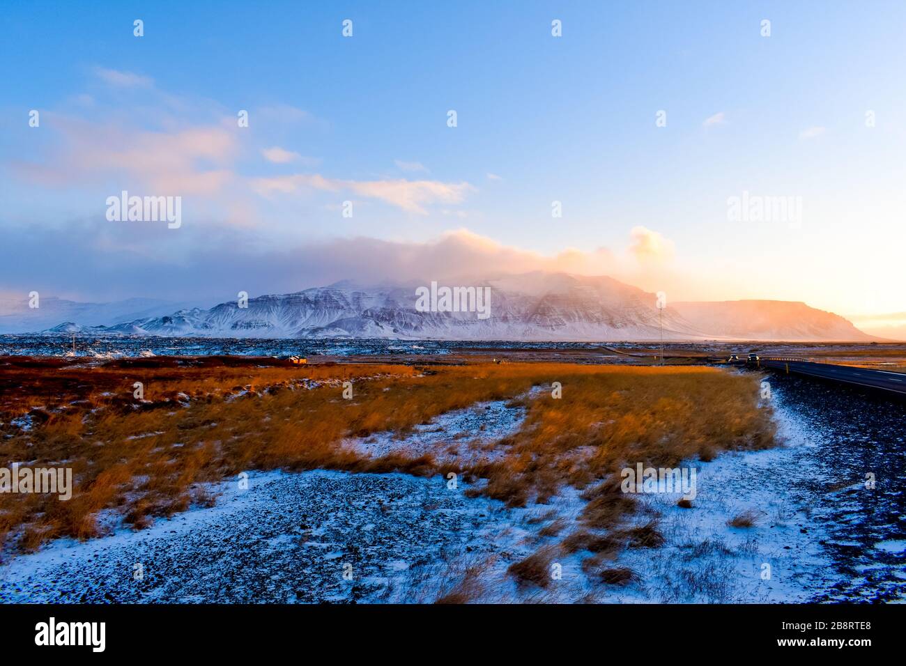 Ein Blick vom Straßenrand in Island mit herbstlichen Feldern und Bergen über den Horizont während der goldenen Stunde Stockfoto