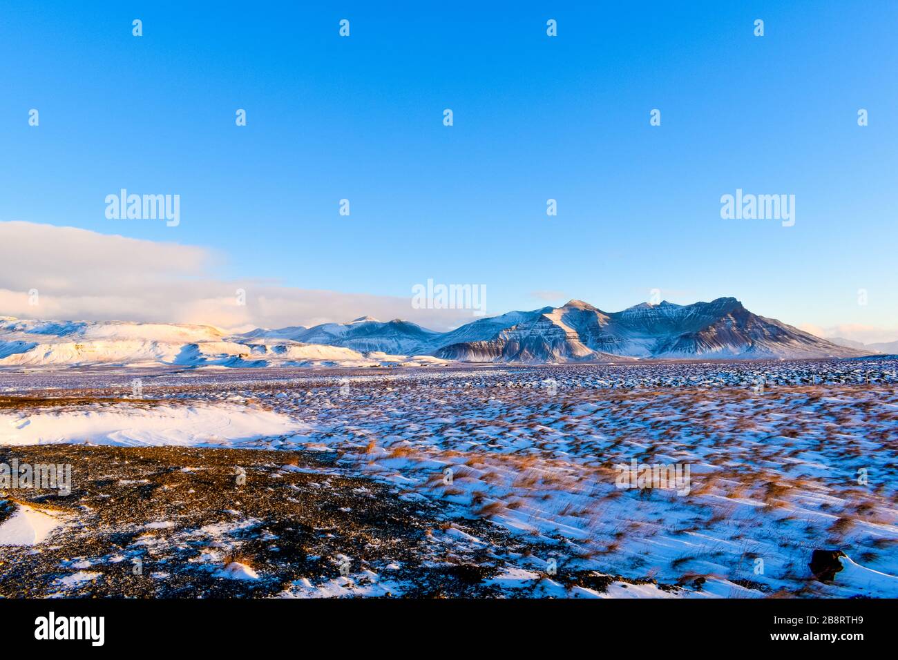 Ein schneebedecktes Feld und Berge in der Ferne Stockfoto