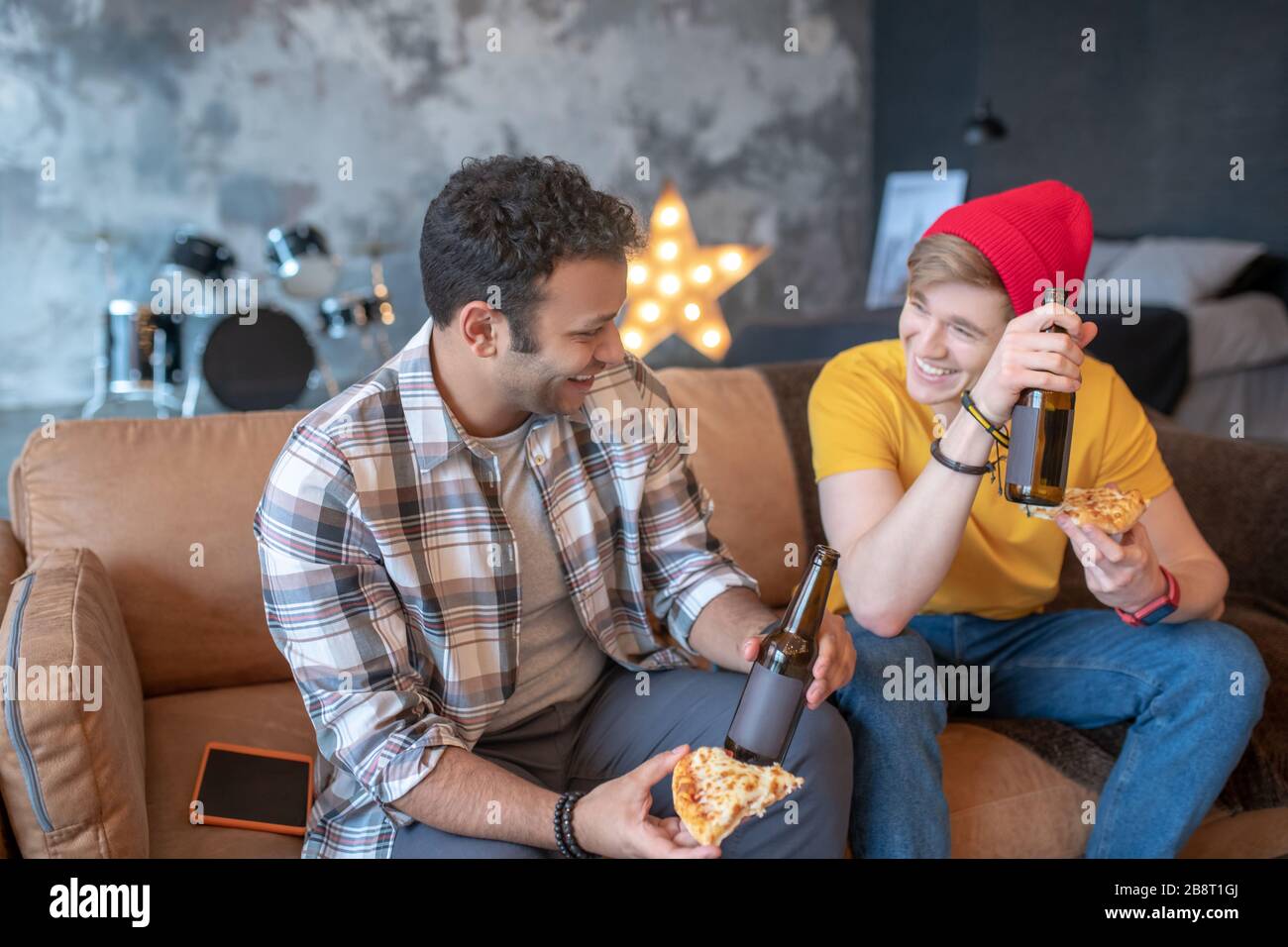 Zwei junge Männer essen Pizza und trinken Bier Stockfoto