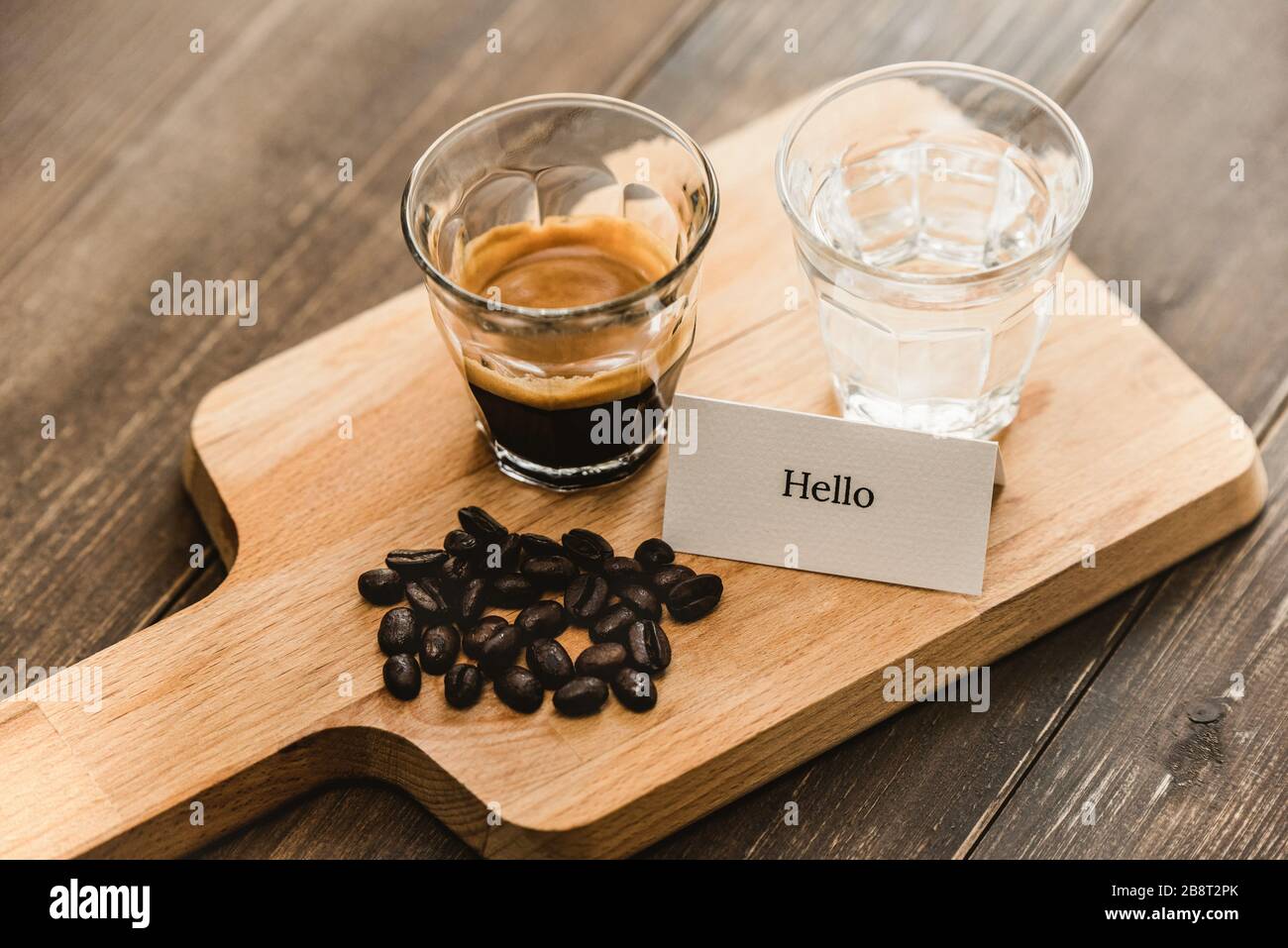 Frisch gebrühter schwarzer Espresso-Kaffee und Wasser in Schussgläsern, serviert auf einer zum Trinken bereiten Holzplatte Stockfoto