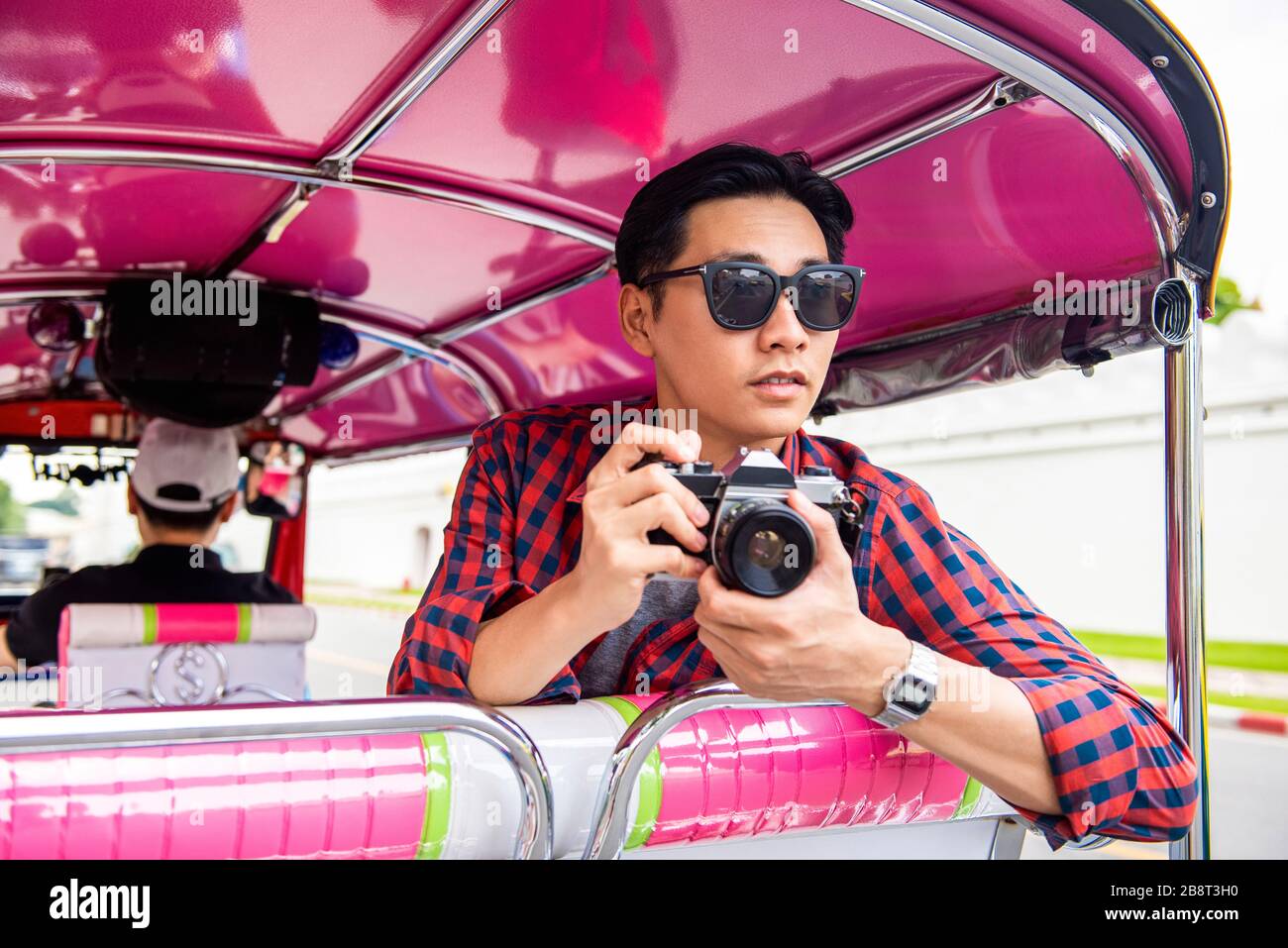 Schöne männliche asiatische Touristen, die während der Sommerferien mit dem Tuk-Tuk-Taxi in Bangkok Thailand Kamera halten Stockfoto