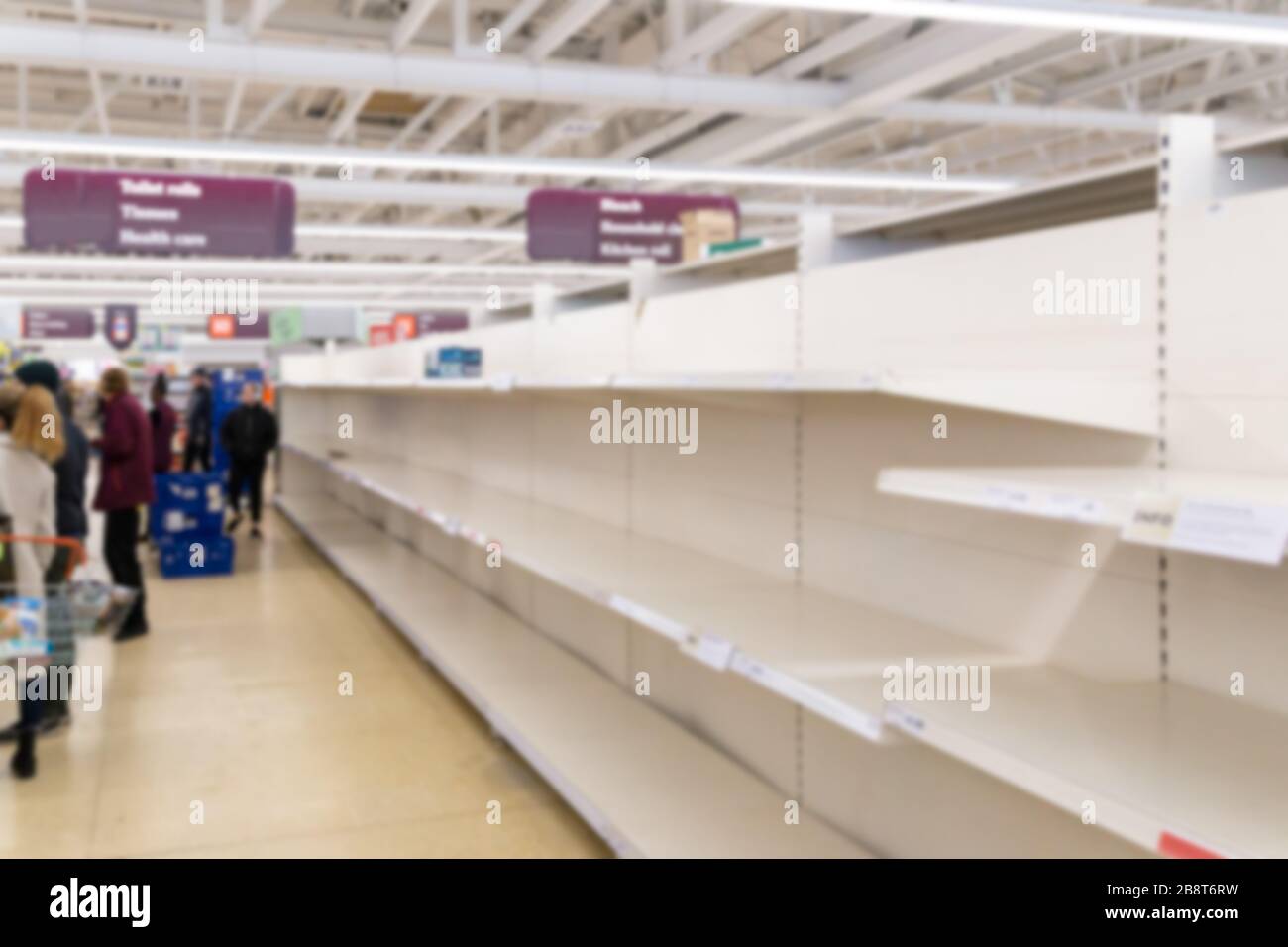 Verschwommenes Innenhintergrundbild leerer Supermarktregale aufgrund von Covid-19, Coronavirus, induzierter Lagerhaltung Stockfoto