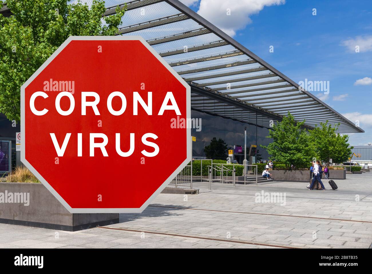 Konzeptbild mit großem roten Coronavirus Warnschild vor dem Heathrow Terminal, Konzept für Reisebeschränkungen Stockfoto