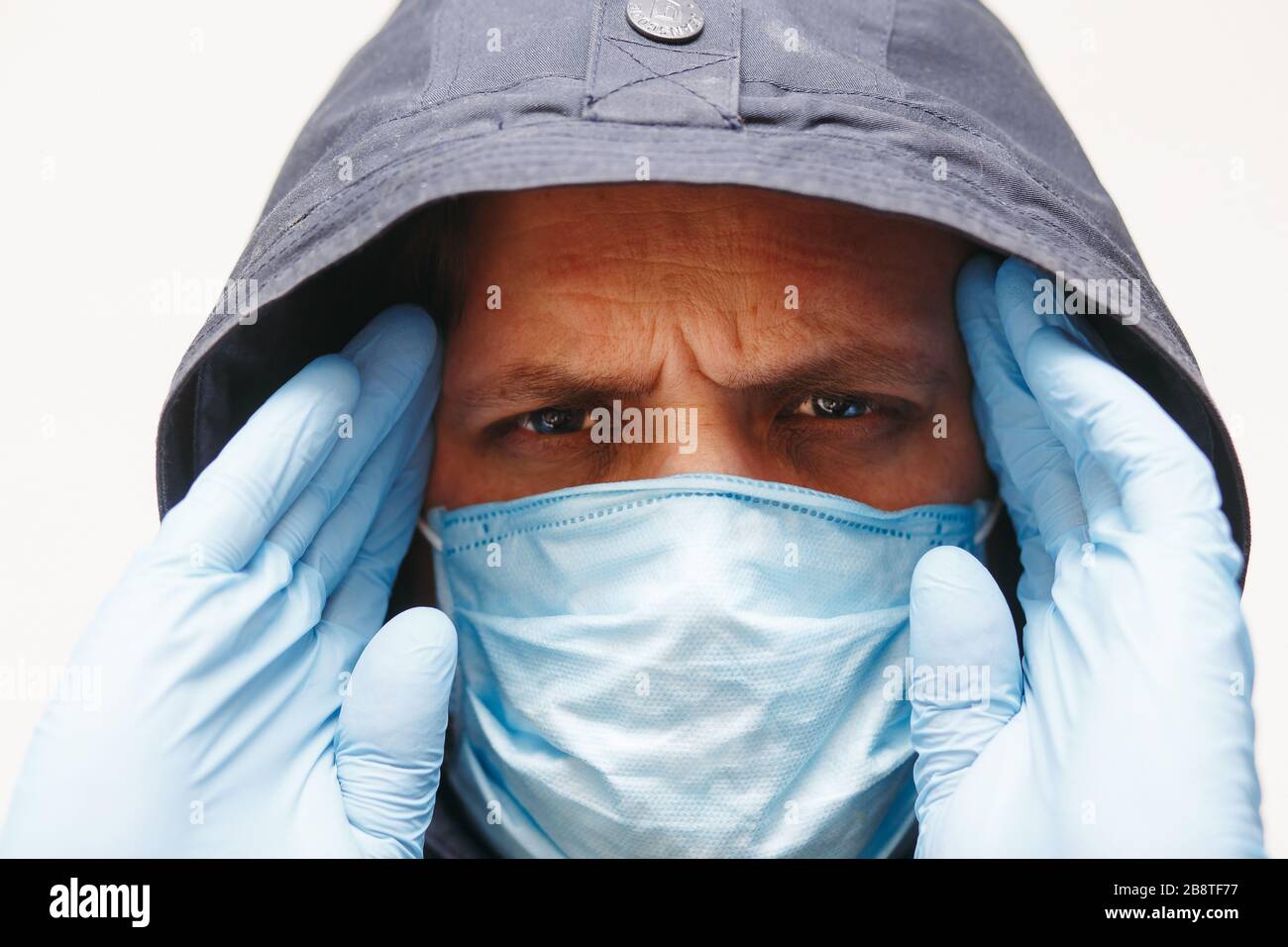 Mann in der Haube mit Maske, um ihn vor Coronavirus zu schützen. Corona-Virus-Pandemie. Junger Mann mit medizinischer Maske isoliert. Person in der Haube mit medizinischer Maske. Stockfoto