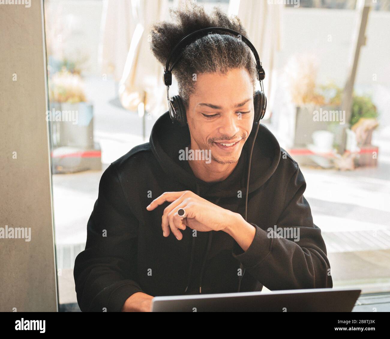 Kreativer afro-amerikanischer Mann mit seltsamen Haaren studiert und erstellt neue Inhalte für seinen persönlichen Blog, lateinamerika arbeitet an Web-Projekt, lebensam Stockfoto