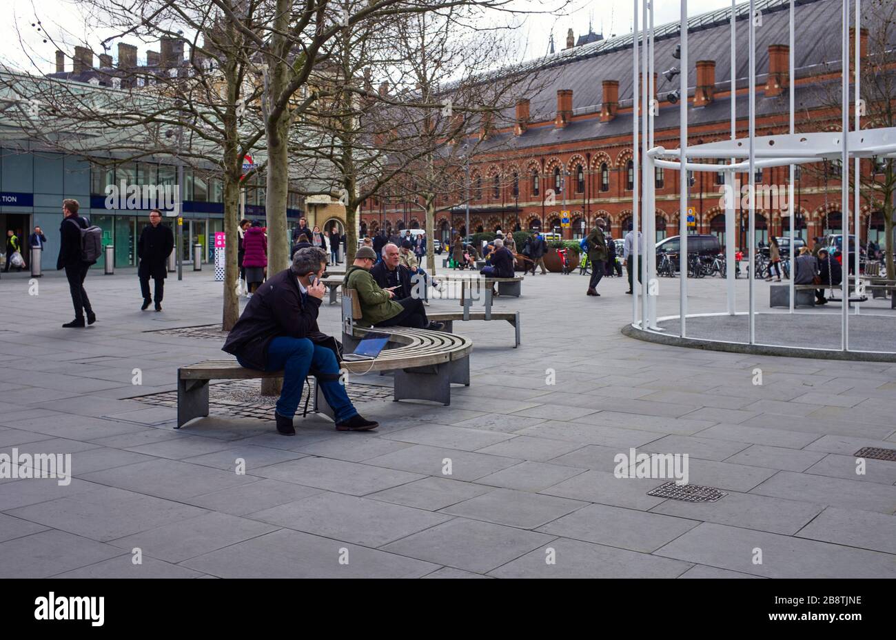 Menschen, die die Woche vor der Covid-19-Krise vor dem Kings Cross und der Station St Pancras sitzen Stockfoto