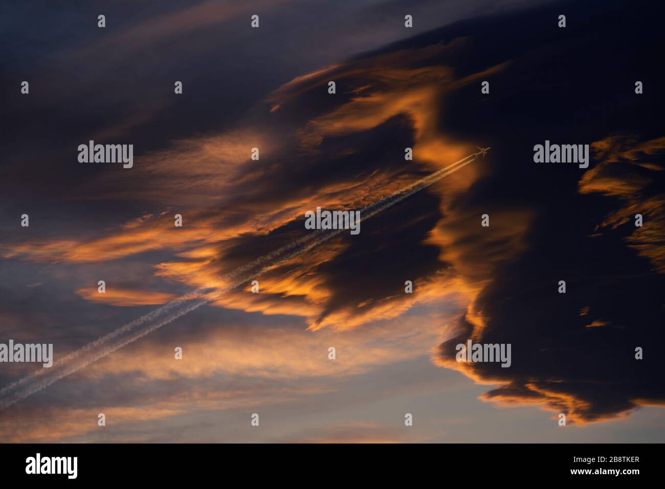 Das kommerzielle Flugzeug fliegt hoch oben am Himmel in dunkle schwarze Wolken. Düstere Atmosphäre. Stockfoto