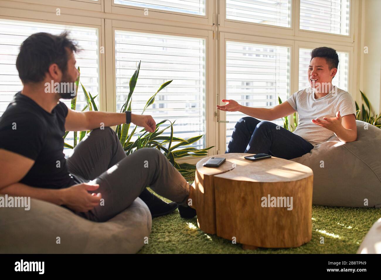 Zwei junge Geschäftsleute unterhalten kleine Gespräche in der Lounge oder im Chill-out-Bereich im Büro Stockfoto
