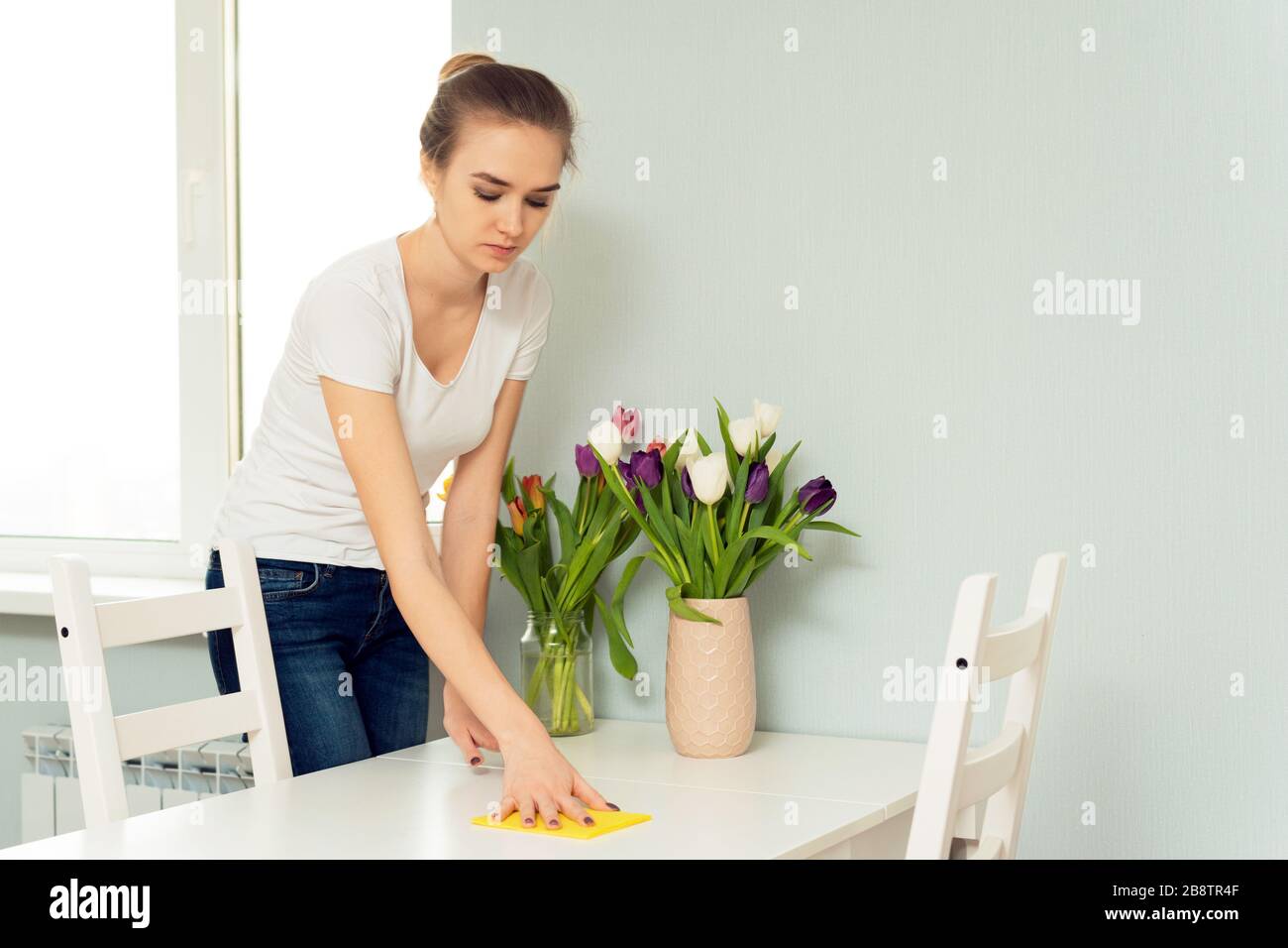Hausfrau wischt Staub vom Tisch, Frau macht tägliche Hausarbeit mit Lappen abstauben. Ordnung und Sauberkeit und Hausaufgaben. Federreinigung. Stockfoto