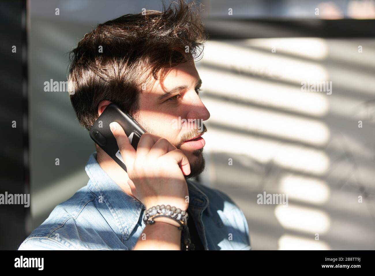 Der junge Geschäftsmann spricht auf dem Handy oder Smartphone im Büro Stockfoto