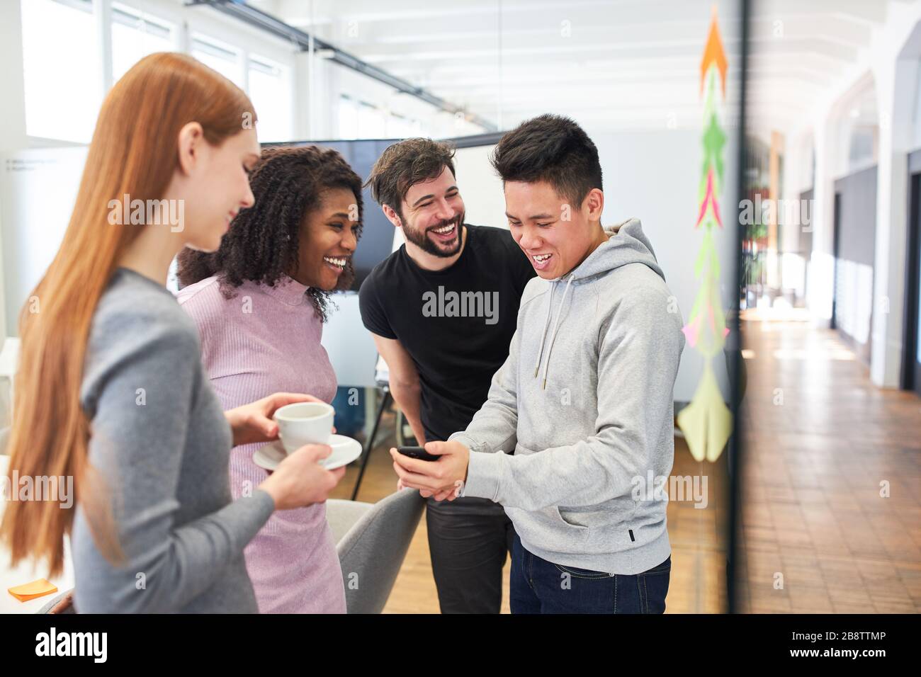 Kollegen im Startup-Team haben Spaß und Lachen über SMS auf ihren Smartphones Stockfoto