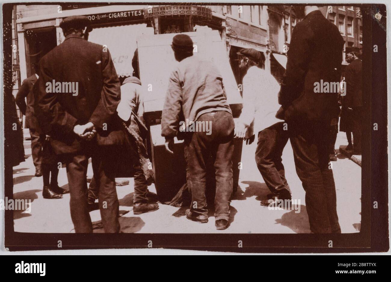 Charaktere, die eine Kiste auf der Straße tragen. "Personnages transportant une caisse dans la rue". Photographie anonyme. Aristoteles. Paris, musée Carnavalet. Stockfoto