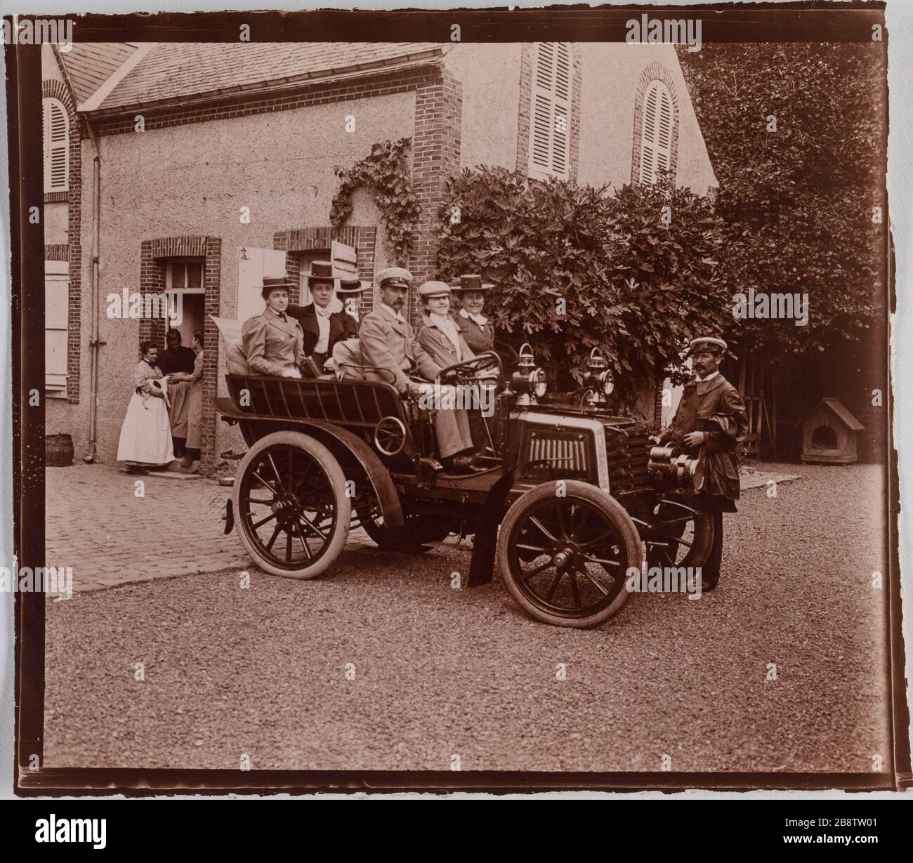 Eine Gruppe von Menschen in einem Motorwagen hielt vor einem Haus. "Groupe de personnes dans une voiture à moteur à l'arrêt devant une maison". Photographie anonyme. Aristoteles. Paris, musée Carnavalet. Stockfoto
