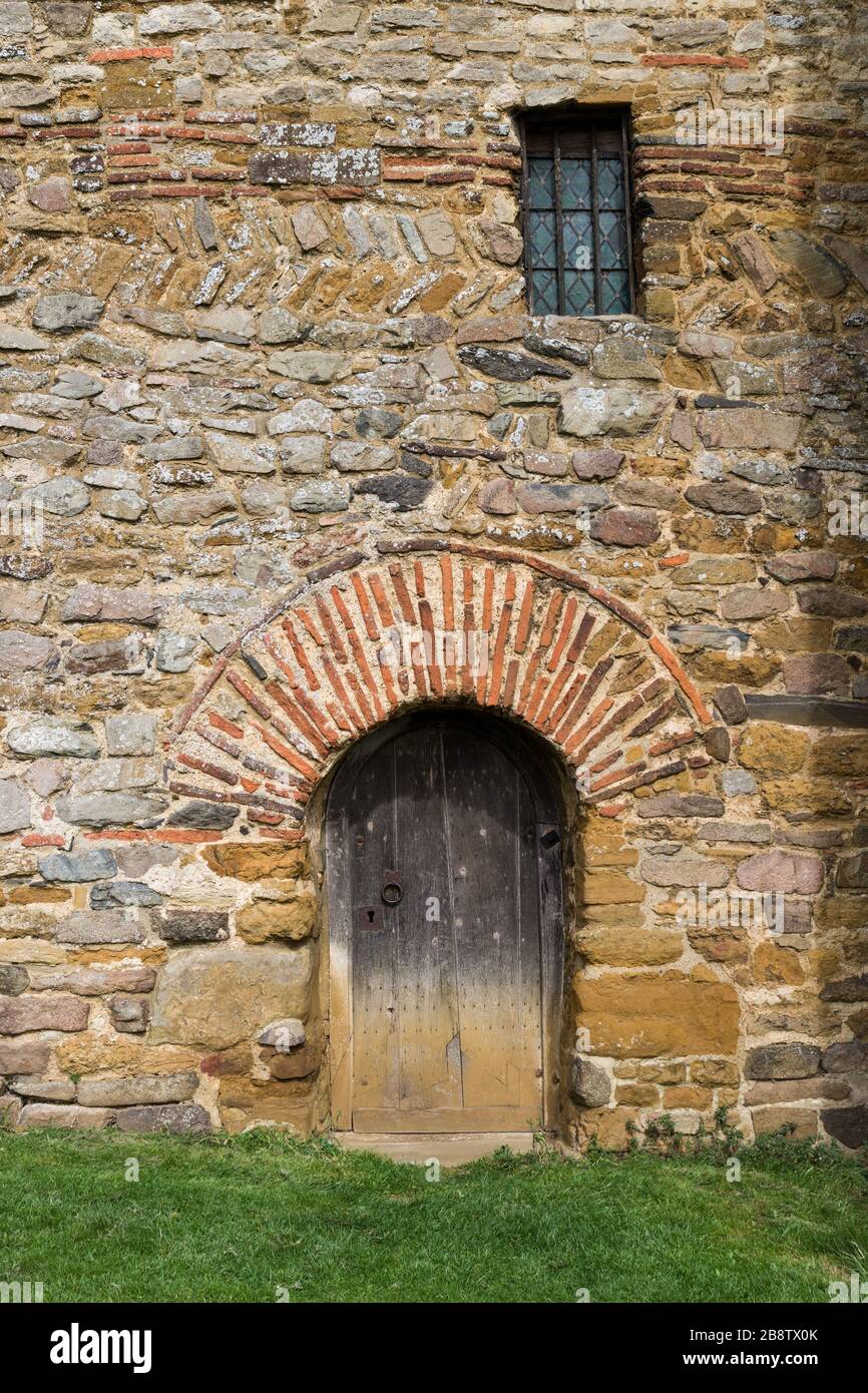 Tür, mit einem römischen Torbogen aus Backstein, an der Außenseite der sächsischen Kirche von Allerheiligen, Brixworth, Northamptonshire, Großbritannien Stockfoto