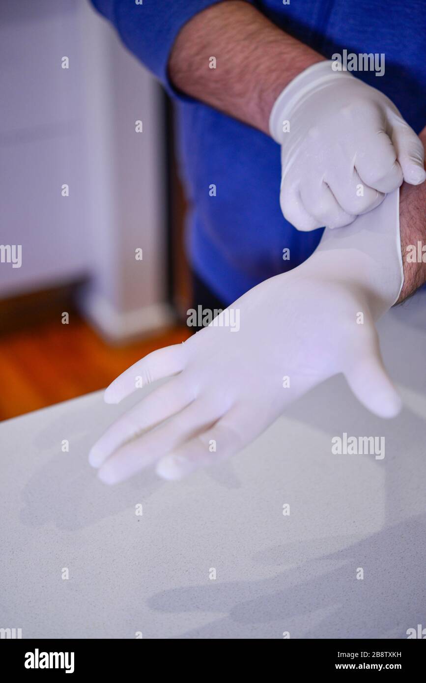 Health Professional, der weiße Latexhandschuhe Coronavirus COVID-19 anlegt Stockfoto