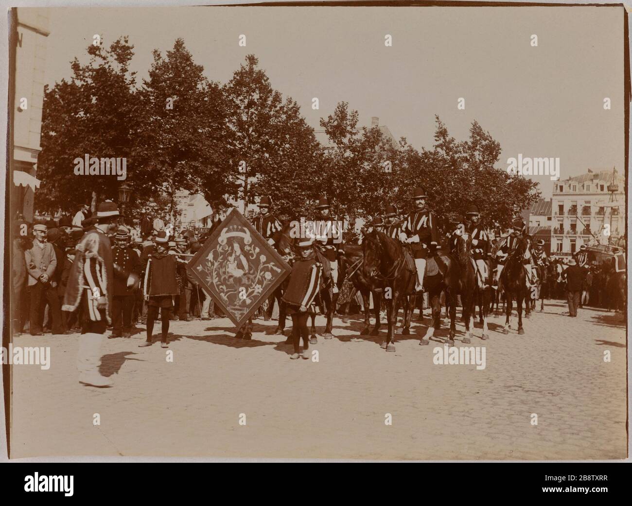 Die Kavalkade von Landjwell. Prozession der Pferdefahrer, ein Dreiecksbanner mit der Jungfrau Maria und Jesuskind vor der Prozession. La Cavalcade de la Landjwell. cortège de cavaliers à cheval, une bannière de forme triangulaire avec la Vierge Marie et l'Enfant Jésus à l'avant du cortège. Hollande? Photo Club de Paris. Paris, musée Carnavalet. Stockfoto