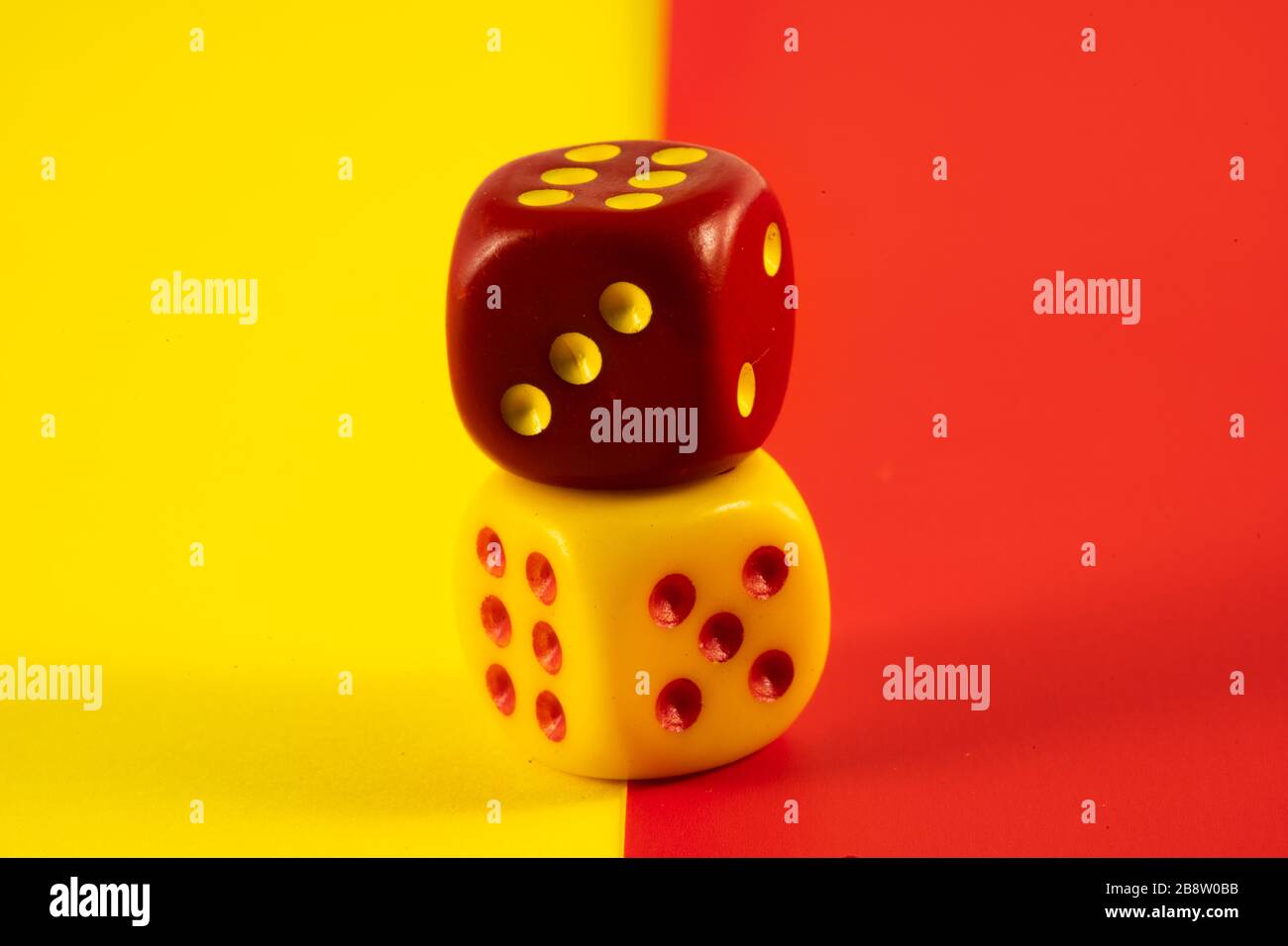 Glückswürfel. Zwei rote und gelbe Würfel auf rotem und gelbem Hintergrund, Glückssymbol Stockfoto