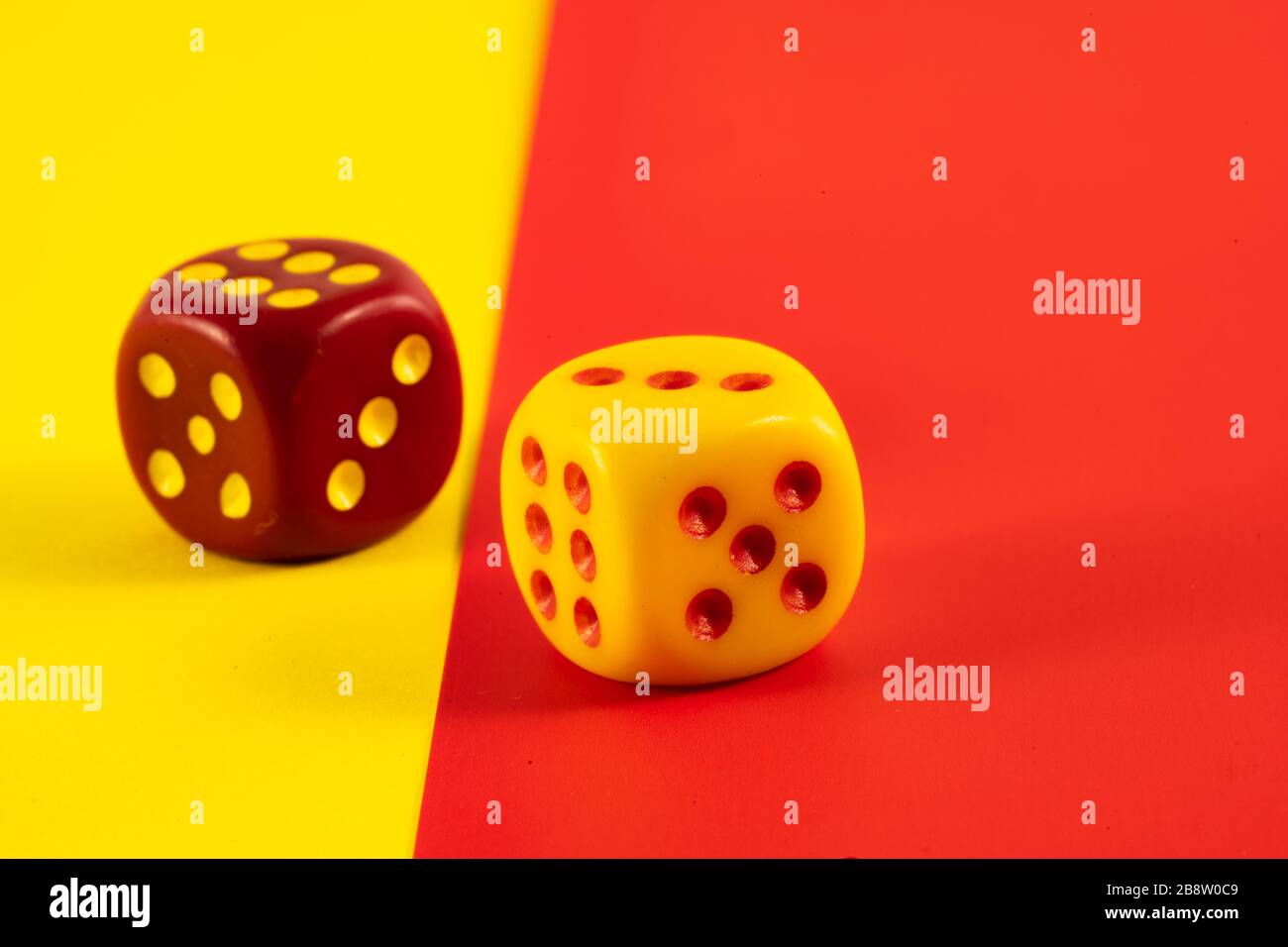 Glückswürfel. Zwei rote und gelbe Würfel auf rotem und gelbem Hintergrund, Glückssymbol Stockfoto