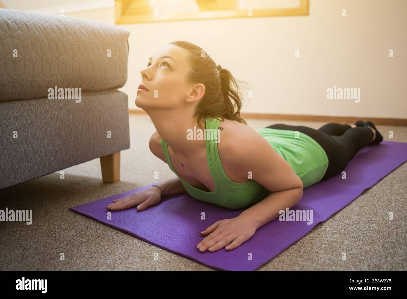 Junge Frau übt zu Hause Yoga aus. Bhujangasana/Cobra Posieren Stockfoto