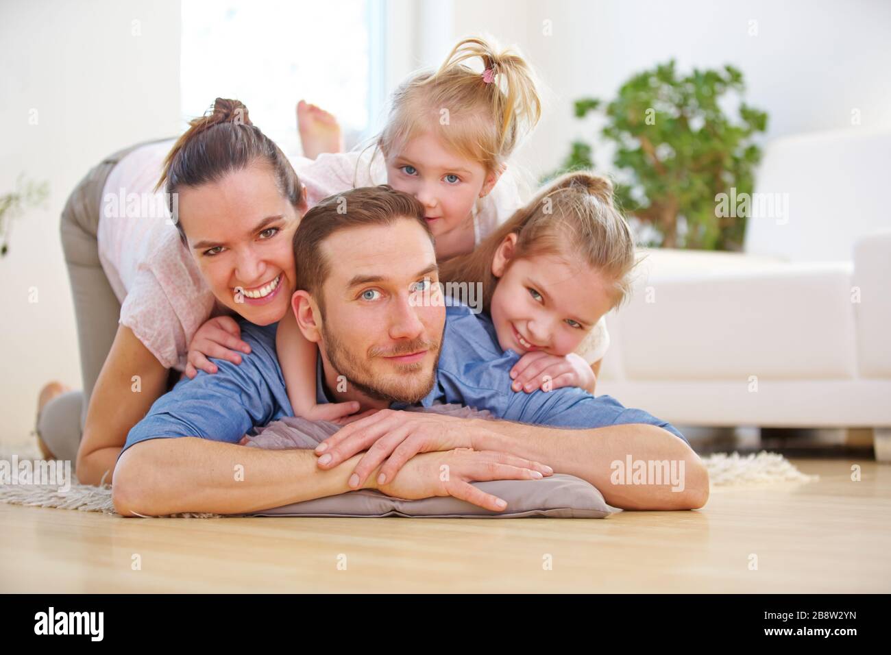 Glückliche Familie und zwei Kinder liegen zu Hause im Wohnzimmer Stockfoto
